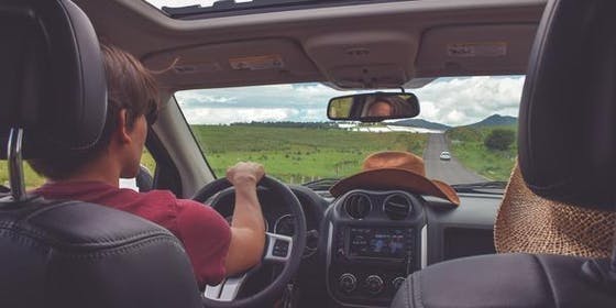 Teen driving a car down a long road