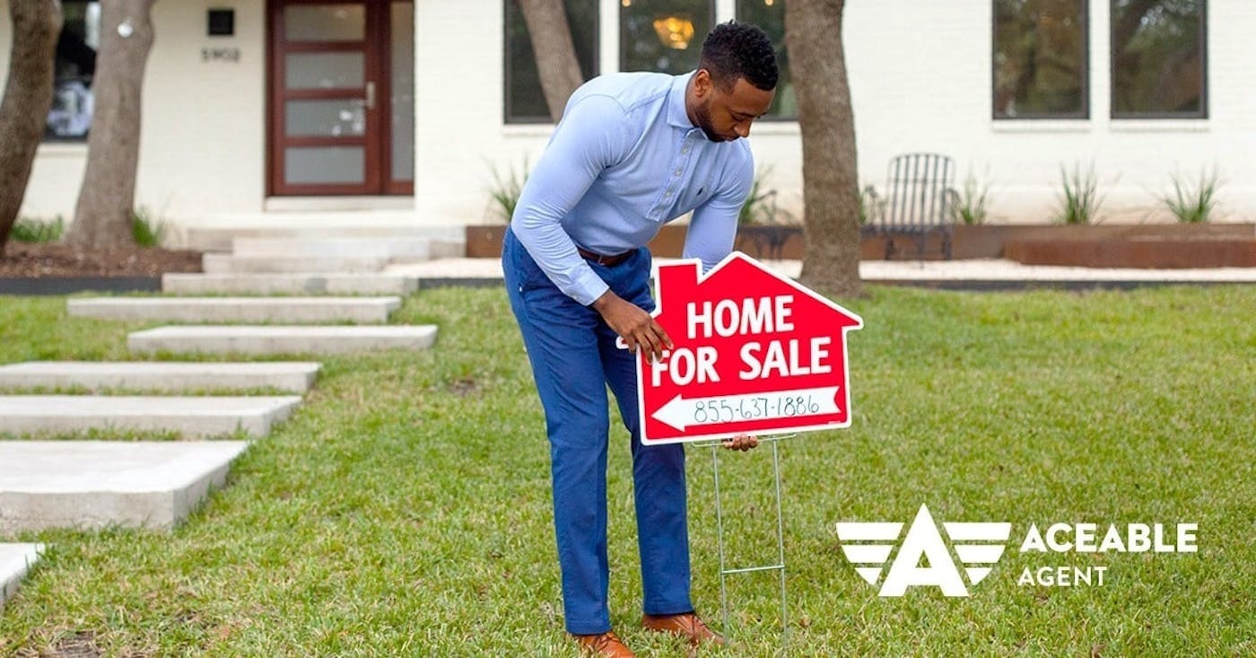 man setting up home for sale sign