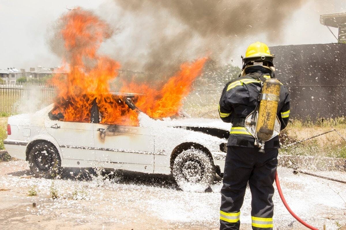 firefighter putting out burning car