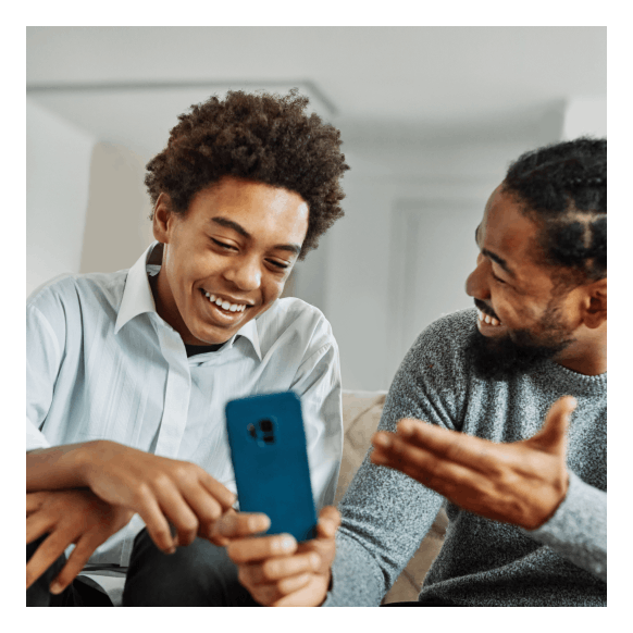 Father and son laughing while looking at a mobile phone