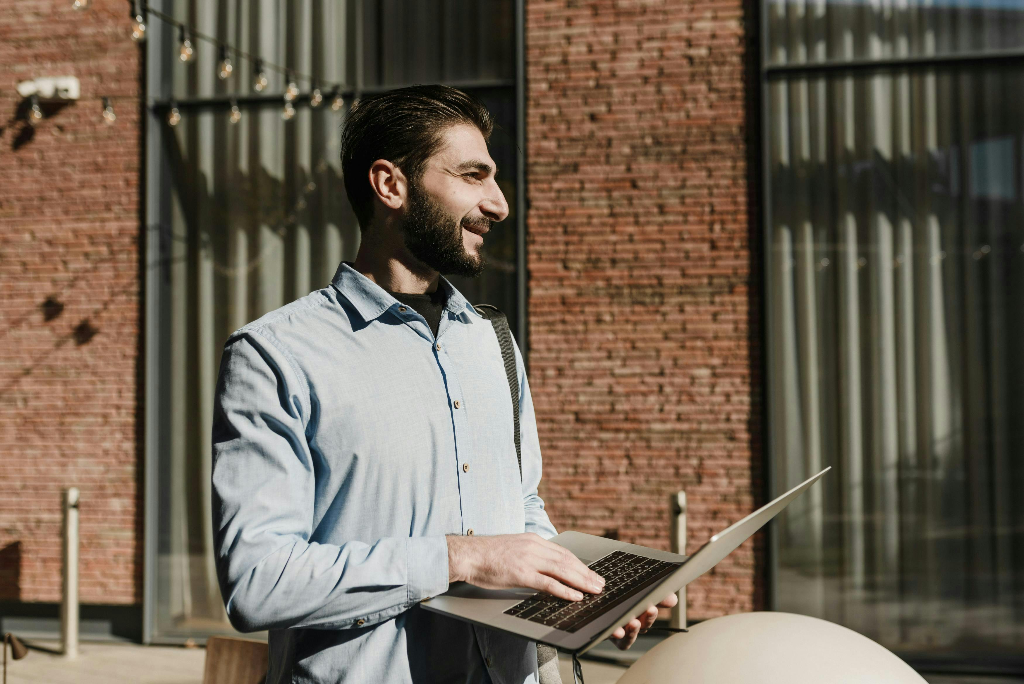 man walking and smiling with his laptop