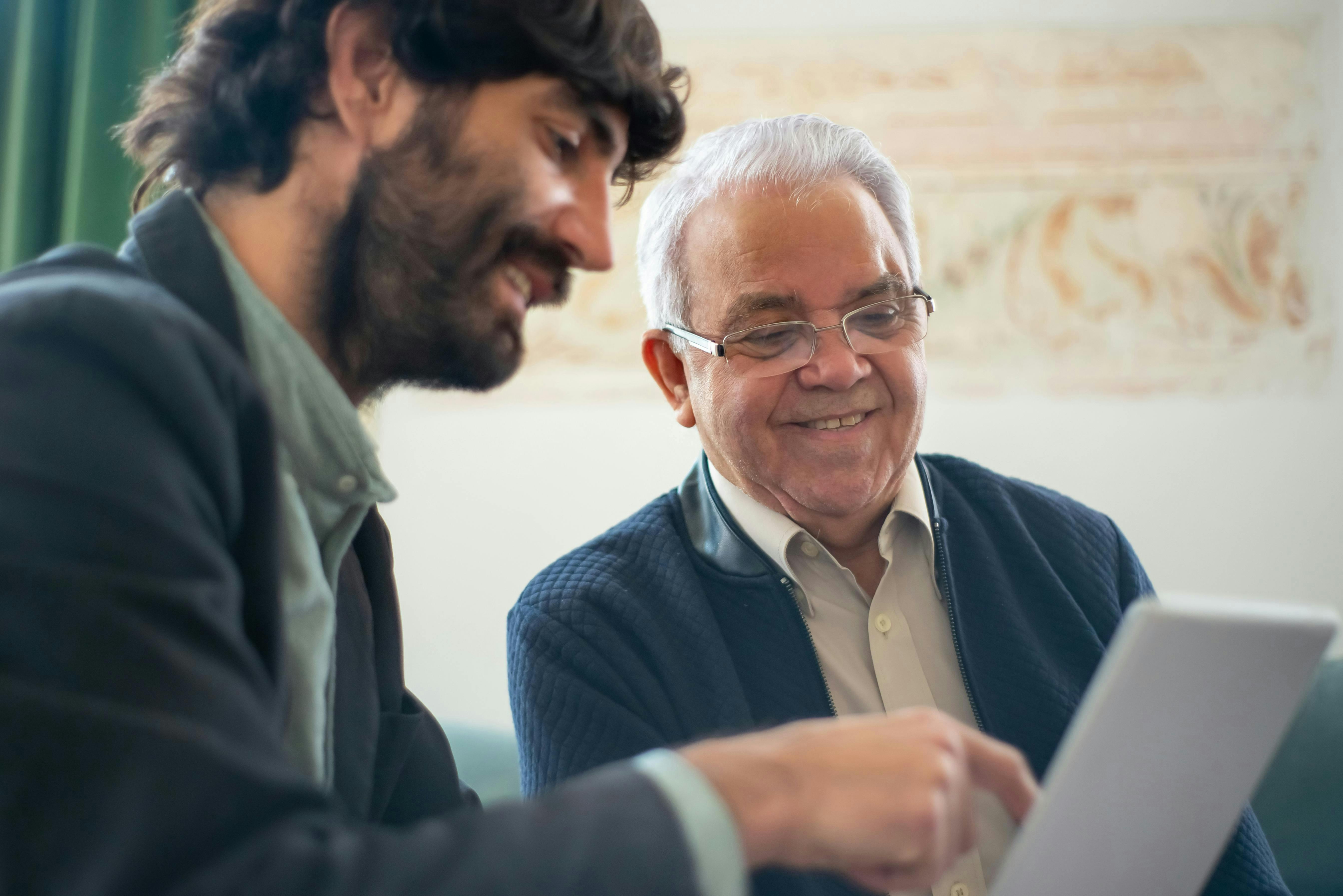 Two men smiling and looking at a piece of paper