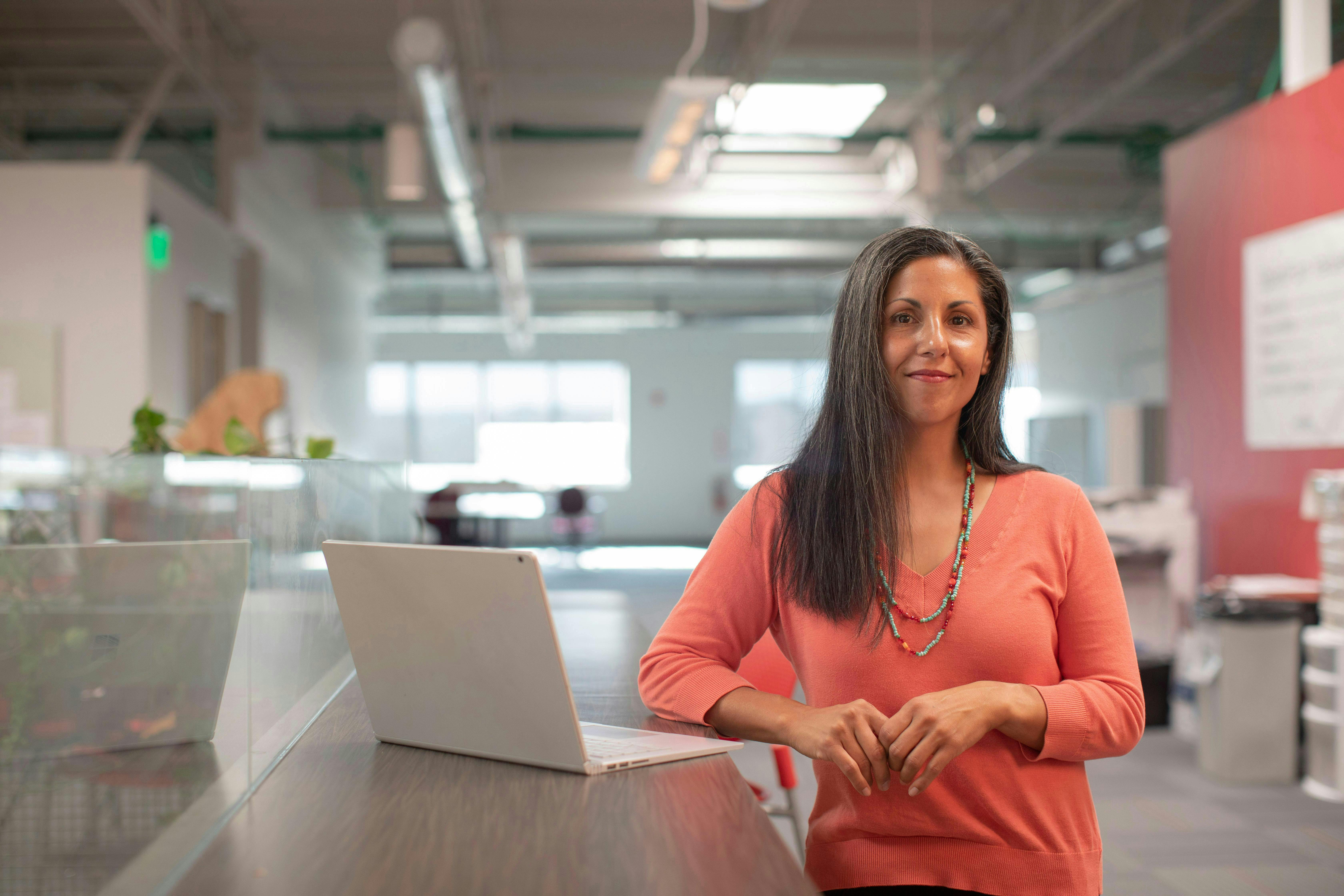 woman in a office smiling and has her laptop