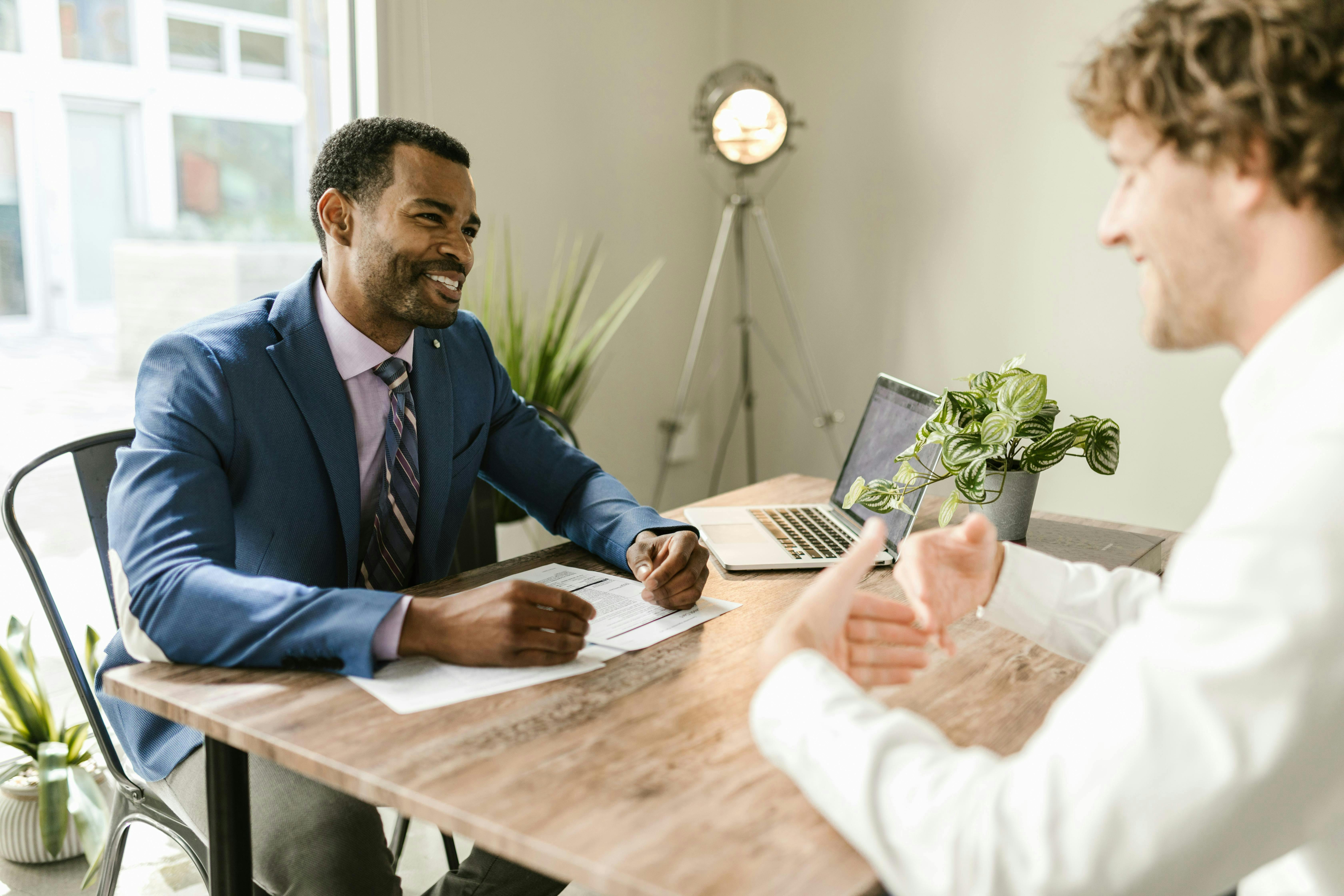 2 businessmen talking at a desk