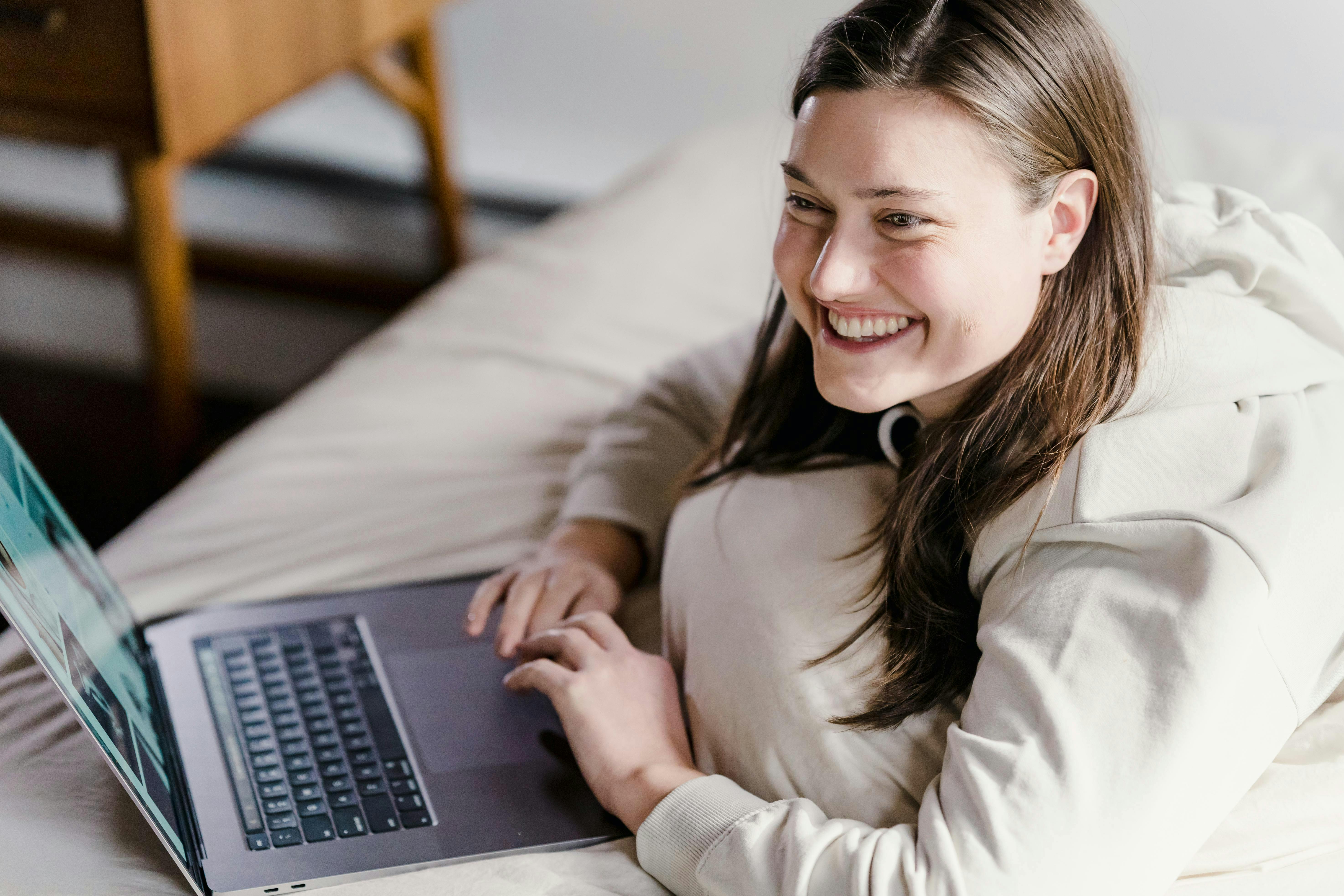 woman laying on bed and on her computer