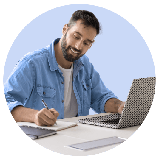 Man taking notes in front of a laptop