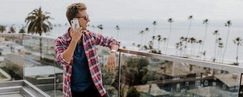 man on phone with palm trees in back