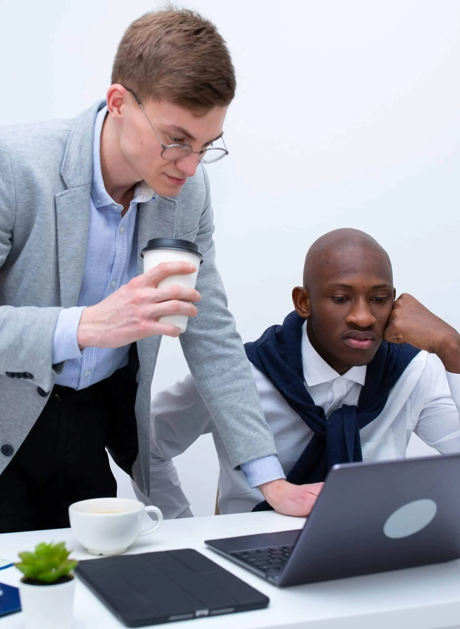two men discussing while looking at laptop