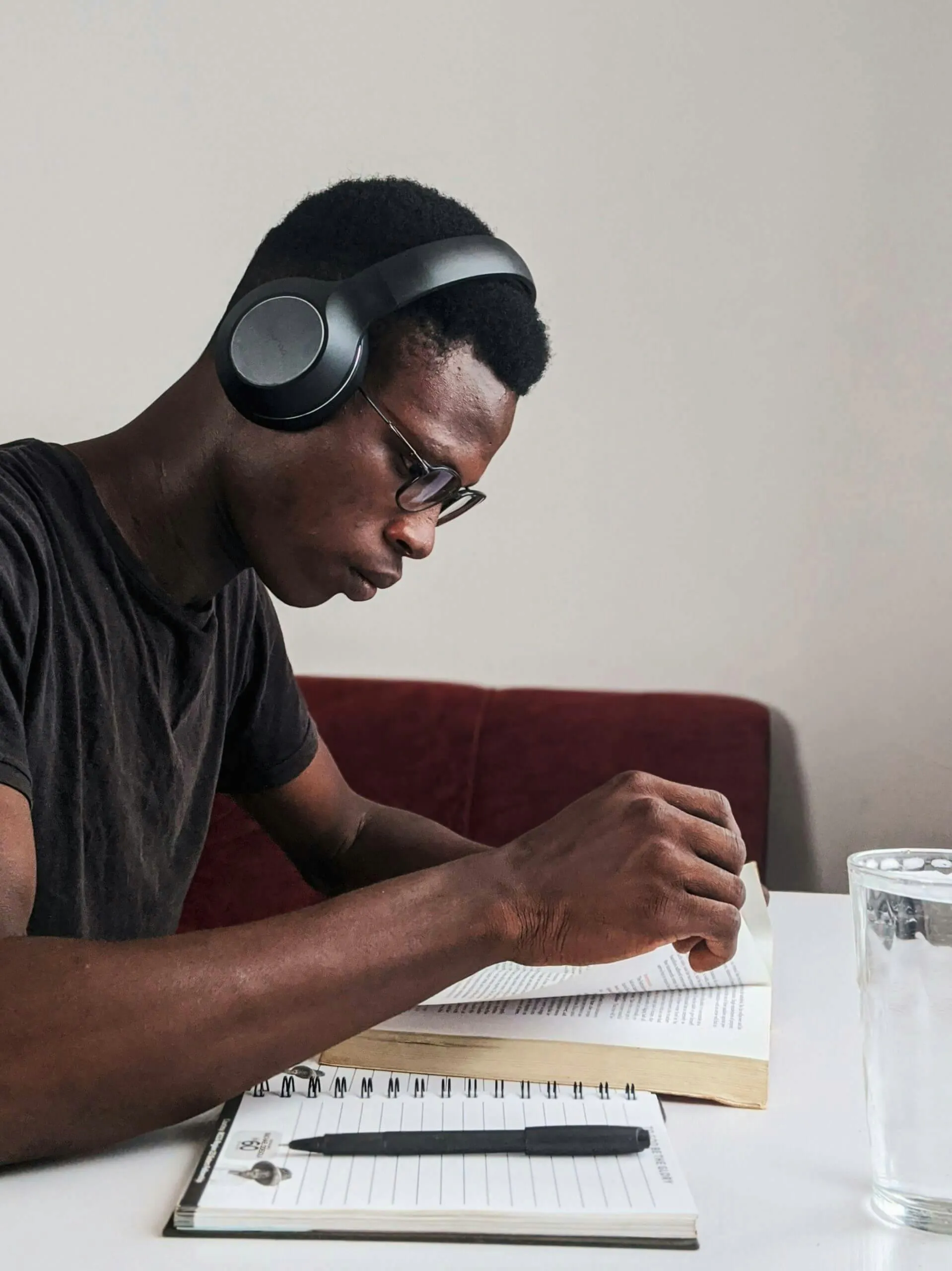 man listening to headphones and studying with pen and paper