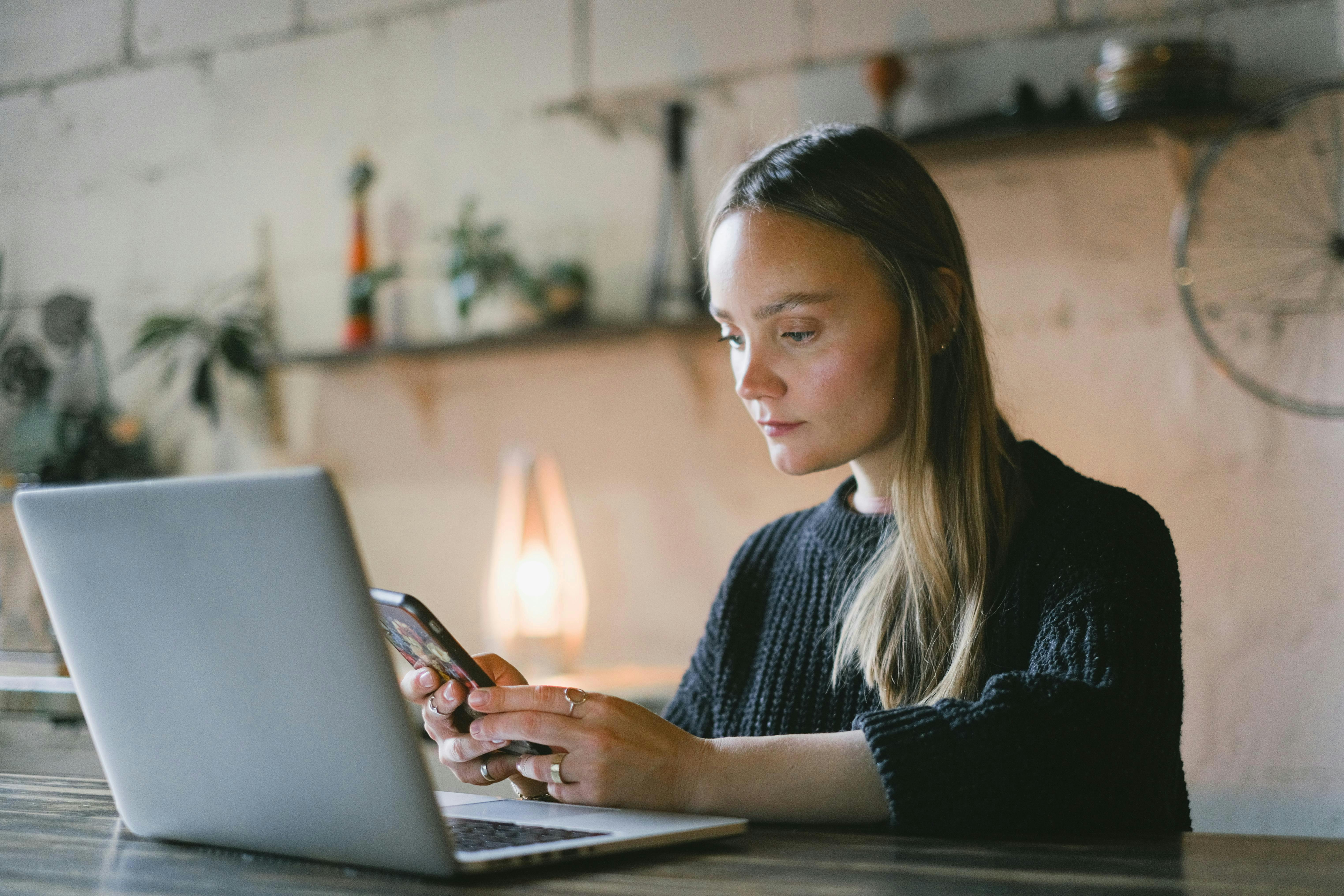 lady in kitchen on her phone with laptop